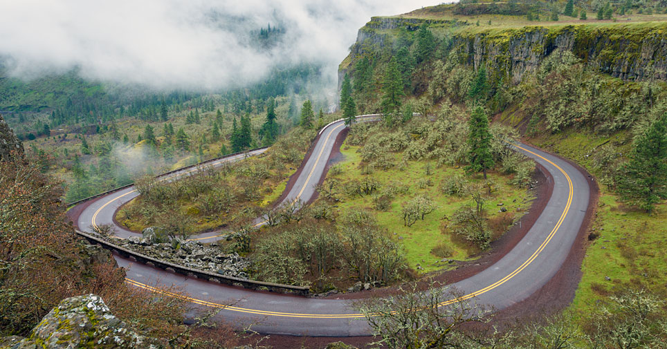 Rowena Loops, a winding road through lush forest land with low level clouds.