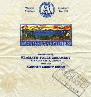 Crater Lake drawing with evergreen trees on shore & a sun set. Reads "Crater Lake Butter manufactured by Klamath Falls Creamery"