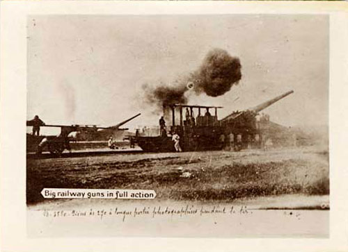 "Big railway guns in full action" printed on photo. Large artillery gun fires and a cloud of dark smoke shows out the barrel. 