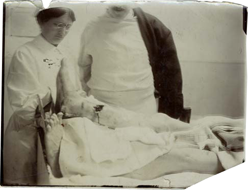 A nurse and doctor look over the leg wound on a soldier.