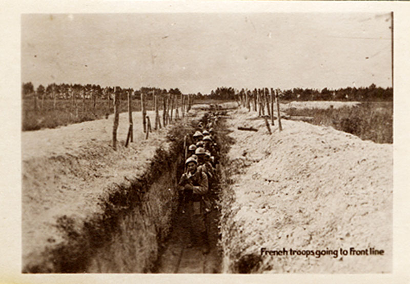 Trench viewed from one end looks downward at a long row of men in helments and combat uniforms.