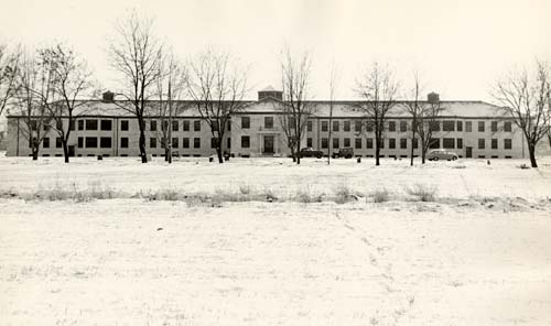 Eastern Oregon State Hosptial shown in winter with bare trees in front and snow covering ground.