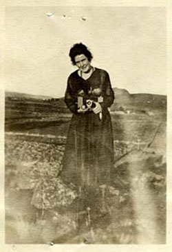 Enid MKern stands outside holding what looks like a camera, circa 1918.