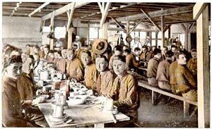 Dozens of soldiers sitting in a mess hall eating a meal.