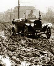 Model T Ford driving on muddy road with bad ruts