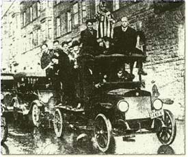Eight people pile into and on top of a model T car to drive through the street in celebration.