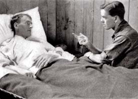 Soldier lies in hospital bed talking to therapist.