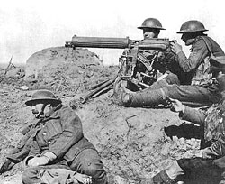 Photo of soldiers sitting on the ground an manning a large gun on a stand.