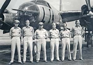 6 men in military uniforms stand in front of a bomber aircraft with "L" and the number 14 printed on side.