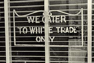 A store window with sign that reads "We cater to white trade only"
