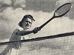 Photo of woman holding tennis racket over tennis net on bright day with few clouds in the sky.