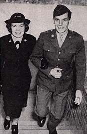 Woman & man, both in military attire, walk up a stairway.