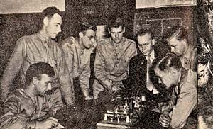 7 men gather around a table to learn military training.