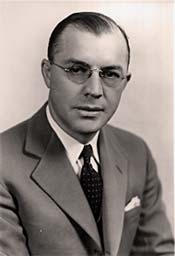 Photo of Milton Eisenhower in suit and tie, wearing glasses.