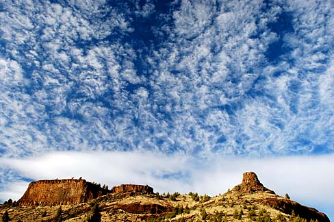 Rock formation shaped like a chimney with blue sky and white clouds in background.