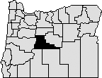 Map of Oregon with a section near the center blacked out to represent Deschutes County.