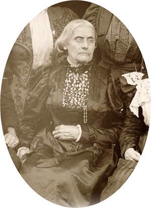 Profile of Susan B Anthony, her hair in a bun, wearing a black dress with a lace collar and a broach at the center.