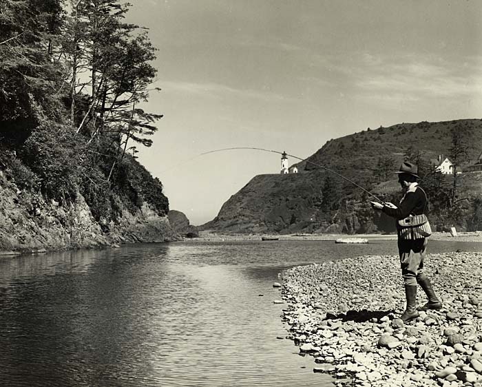 Man on rocky shore fishing in creek.
