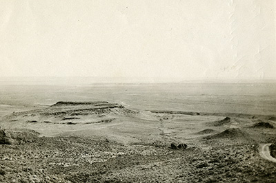 A barren looking landscape with a flat rock formation on the left.