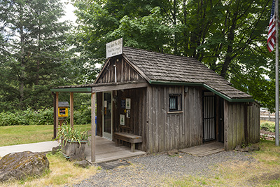 One-story, single room wood plank building with a covered porch. The sign over the door says, "United states post office"