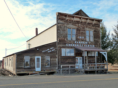 A wooden plank building with "1879 Hardman Community Center" printed on the front.