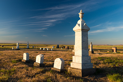 Flat land with short grass and lines of tombstones. Many tombstones look to be of marble.