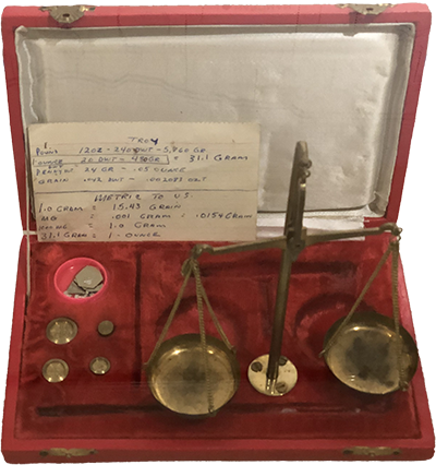 Brass scale in a velvet lined box with a compartment that houses different sized weights.
