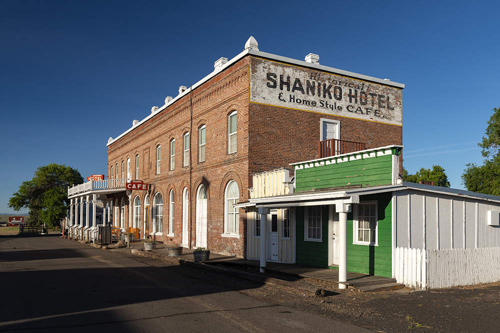 Brick two-story building with "Shaniko Hotel" painted on the side.
