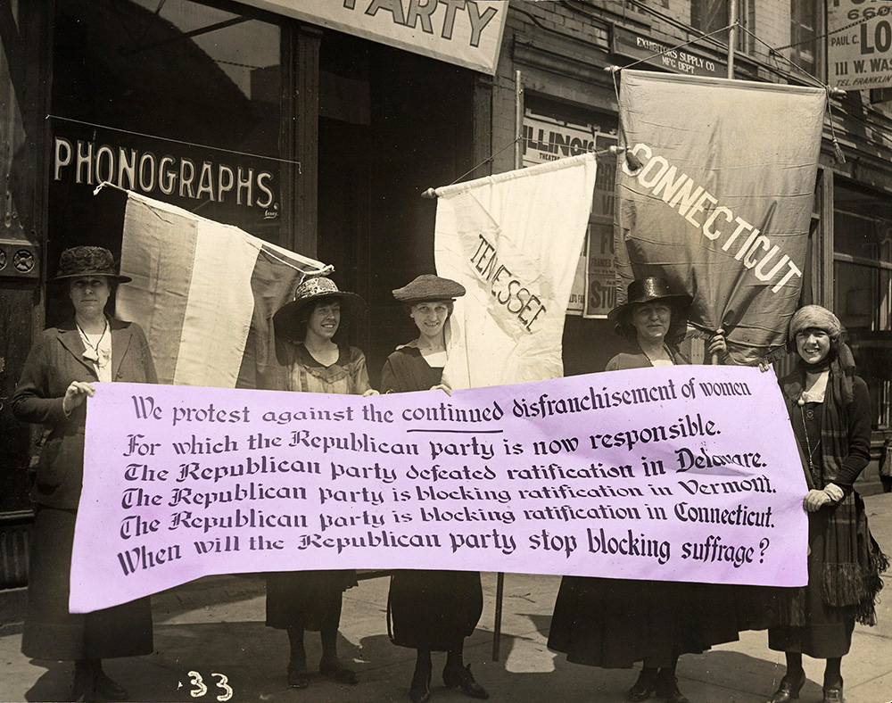 Five women stand on a sidewalk with banners protesting the Republican party blocking suffrage.
