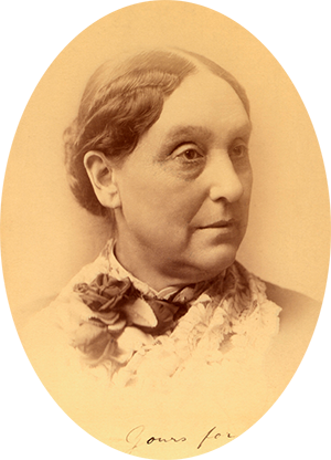 Photo of Abigail Scott Duniway wearing a lace collar over her dress. Her hair is parted down the middle & tied in a bun behind.