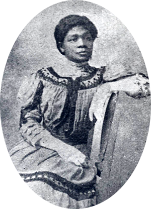 Photo of Hattie Redmond sitting sideways in a chair with her left arm resting on the back of the chair.
