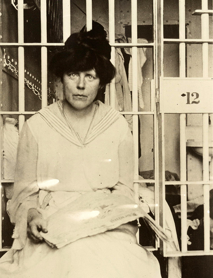 Photo of Lucy Burns with a news paper sitting in a jail cell.