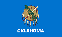 Oklahoma flag has sky blue background with circular rawhide shield of American Indian Warrior, decorated with 6 painted crosses. The lower half of the shield is fringes with 7 pendant eagle feathers. A peace pipe crosses with an olive branch.