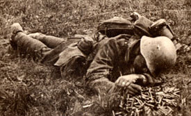 A soldier lying face down on the battlefield.