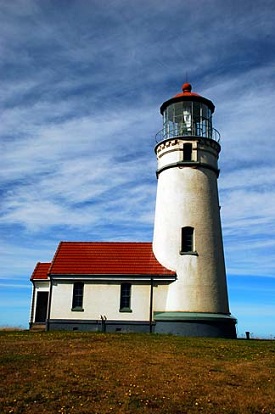 Light house tower with side building sits on a hill.