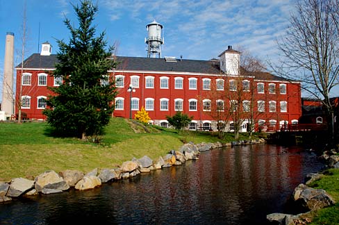 3 story red brick building with water tower in background and creek running in front.