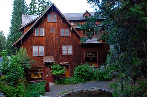 Rustic lodge covered with bark from cedar trees. Shed and dormer style roofs mimic the surrounding mountains.