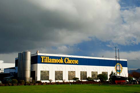 Tillamook Cheese factory building from a distance with a large dark cloud above it.