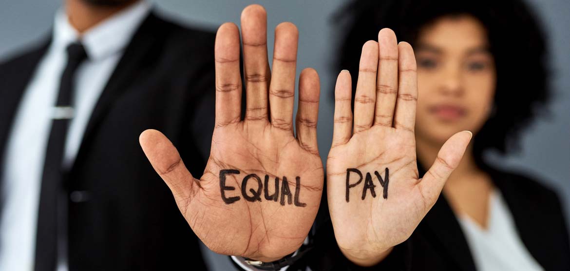 Two hands held with palms facing the viewer that have Equal Pay written on them