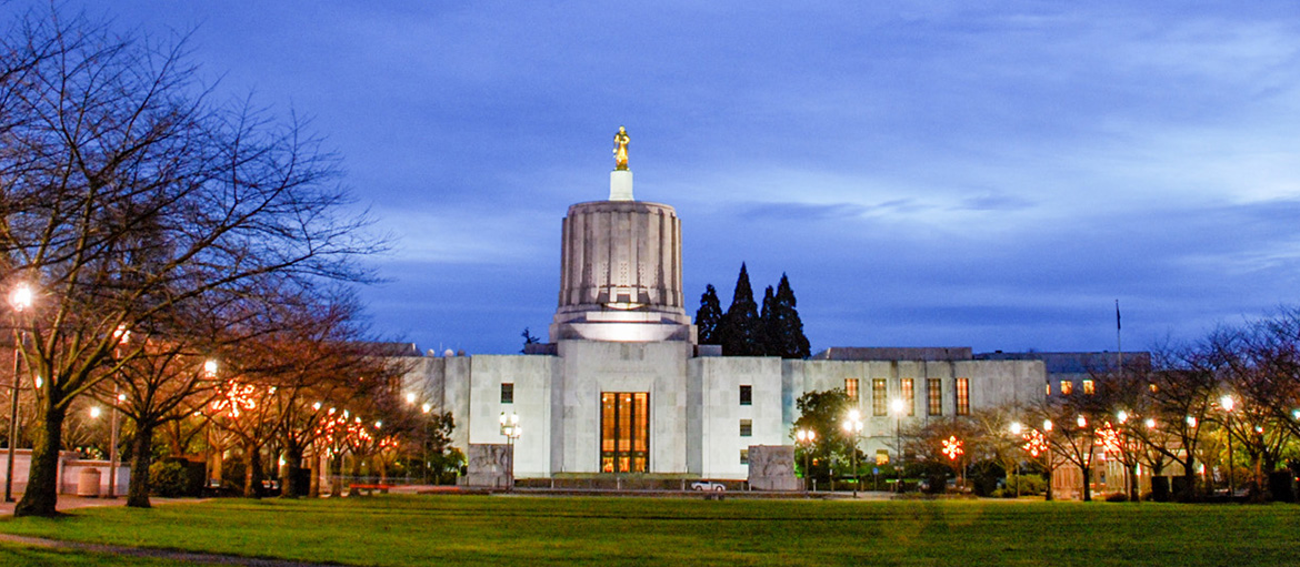 Oregon State Capitol building with gold Pioneer statue at dusk.