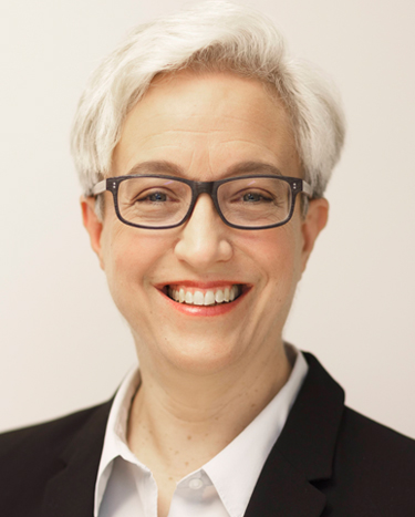 Tina Kotek has short white hair, is wearing glasses and a white shirt with black suit jacket.