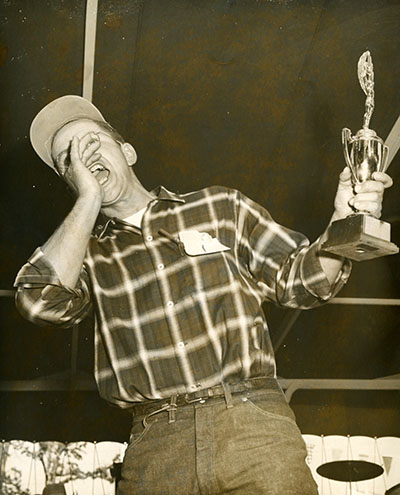 A man yells and holds a trophy