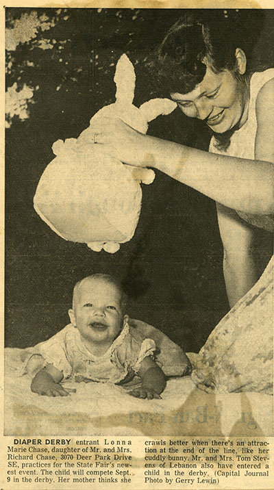A woman holds a stuffed bunny in front of a baby