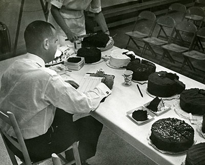 A judge writes on a clipboard at a cake competition