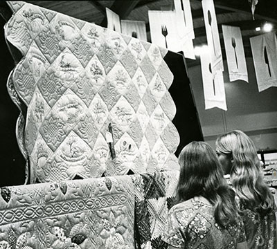 Women look at quilts in a show