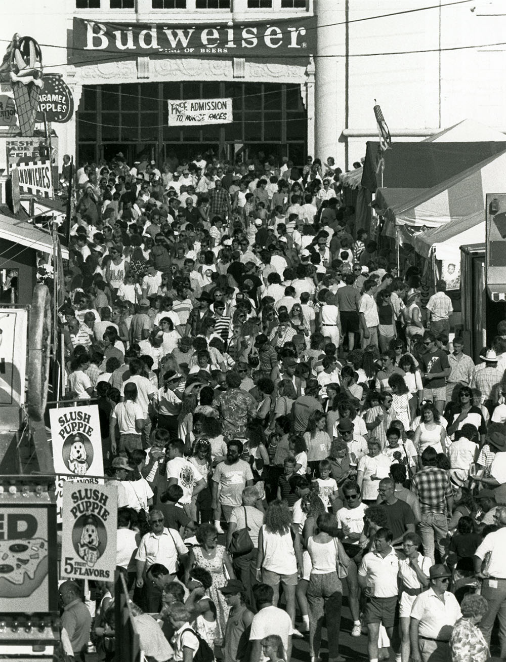 Crowds of fairgoers walk by food booths at the State Fair