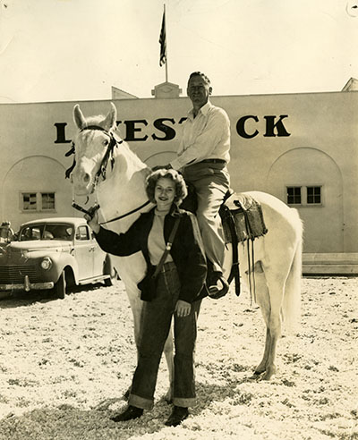 A man and woman pose with a horse