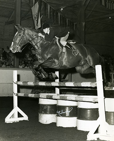 A horse and rider jump an obstacle