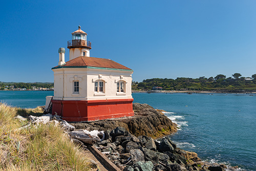 A lighthouse on a rocky out crop by the sea.