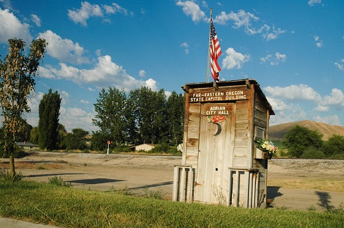 An old outhouse with an American flag flying on top.